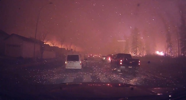 Orange embers from a wildfire fly across a road in Fort McMurray, Alta., in this Wednesday, May 4, 2016 photo taken from dash cam video. THE CANADIAN PRESS/HO - YouTube, Michel Chamberland MANDATORY CREDIT.