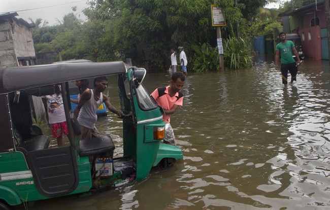 Sri Lankan men push an auto rickshaw stranded in a flooded road after heavy rains in Colombo, Sri Lanka, Monday, May 16, 2016. Flash floods caused by heavy rains have displaced hundreds of families in several parts of Sri Lanka as the Indian Ocean Island is experiencing extreme weather conditions over the last two days. (AP Photo/Eranga Jayawardena).