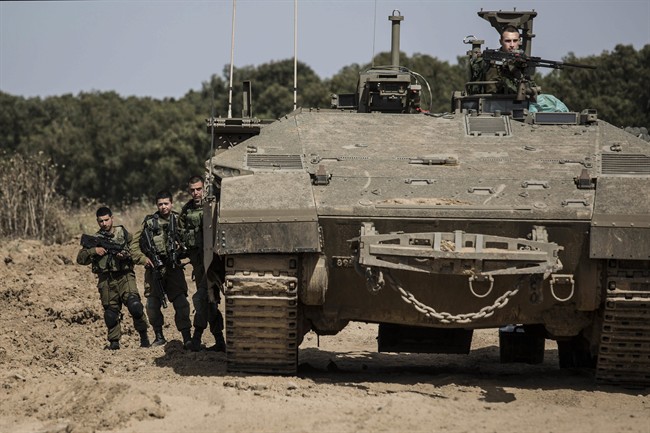 Israeli soldiers stand by a tank near the Israel Gaza border, Wednesday, May 4, 2016. The Israeli army says a tank has fired at a target in the northern Gaza Strip following an explosion on the Palestinian side of the border. The army says it's trying to determine the source of the explosion, which took place on Wednesday. Earlier, a tank fired into Gaza after a mortar shell was launched toward Israeli forces near the southern Gaza Strip. (AP photo/Tsafrir Abayov).