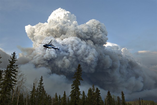 A helicopter flies past a wildfire in Fort McMurray, Alta., on Wednesday May 4, 2016. 