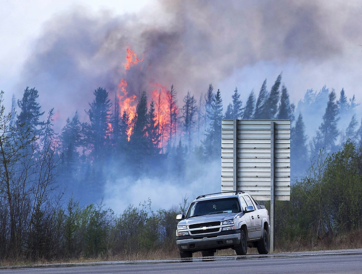 Flames flare up from hotspots from a wildfire along a highway to Fort McMurray, Alberta on Sunday, May 8, 2016. 