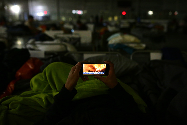 A displaced resident looks at the fire on their mobile phone at a makeshift evacuee centre in Lac La Biche, Alberta on May 5, 2016, after fleeing forest fires north of Fort McMurray.