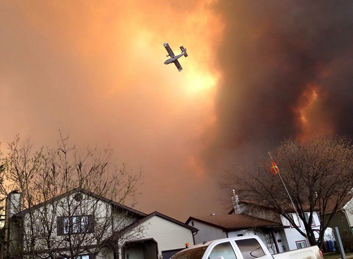 Smoke fills the air as a small plane flies overhead in Fort McMurray, Alberta on Tuesday May 3, 2016.
