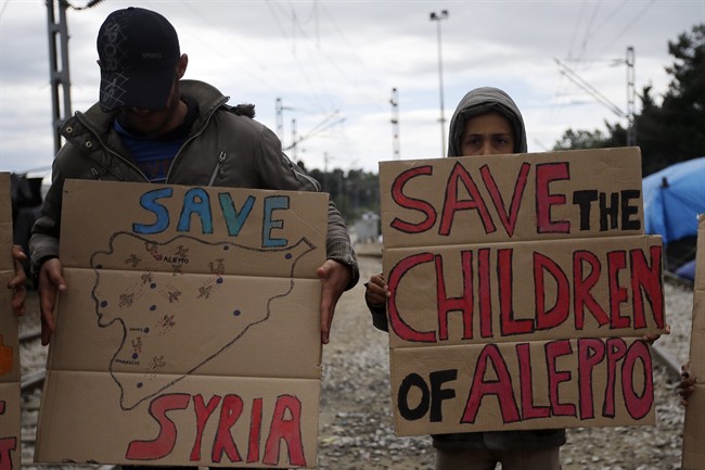 Refugees from Syria holds placards during a demonstration in the northern Greek border point of Idomeni, Greece, Wednesday, May 4, 2016. European Union countries that refuse to accept refugees under proposals to overhaul the EU's failed asylum laws could face large fines for each asylum seeker rejected. (AP Photo/Gregorio Borgia).