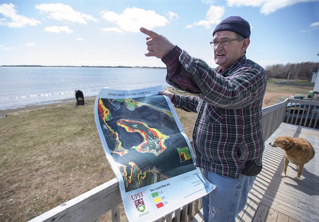 Dave Haley displays a map from the University of Prince Edward Island's climate research lab, showing sea level rise in Lennox Island, P.E.I. on Monday, April 25, 2016. Rising sea levels and coastal erosion threaten the Mi'Kmaq community which has seen a major loss of landmass in the last 50 years. THE CANADIAN PRESS/Andrew Vaughan.