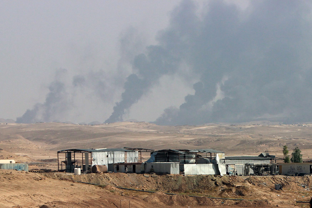 In this Saturday, Oct. 24, 2015, file photo, smoke rises as Iraqi security forces and allied Popular Mobilization Forces shell Islamic State group positions at an oil field outside Beiji, some 250 kilometers (155 miles) north of Baghdad, Iraq. 