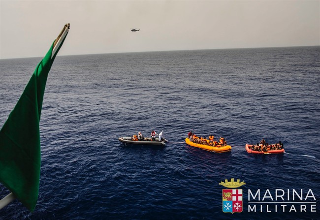 In this photo taken in the Mediterranean Sea, off the Libyan coast, Friday, May 27, 2016, rescuers tow migrants to the Italian Navy ship Vega, after the boat they were aboard sunk. The Italian navy says it has saved 135 migrants from a sinking boat and recovered 45 bodies in the Mediterranean. 