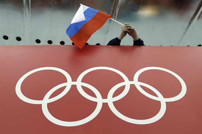 In this Feb. 18, 2014 file photo, a Russian skating fan holds the country's national flag over the Olympic rings before the start of the men's 10,000-meter speedskating race at Adler Arena Skating Center during the 2014 Winter Olympics in Sochi, Russia.