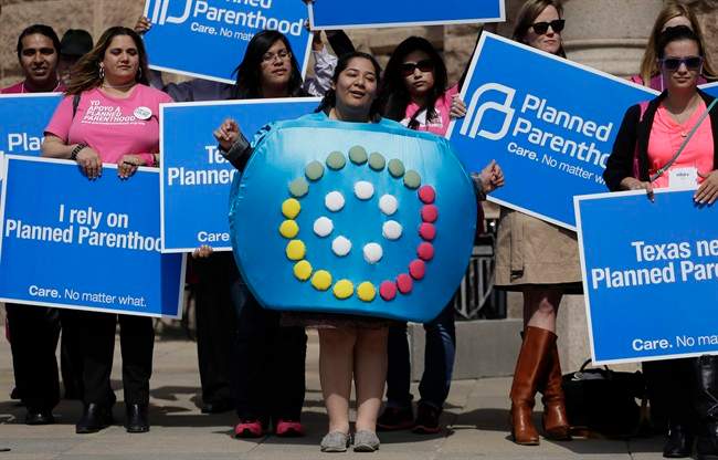 In this March 7, 2013 file photo, Alyssa Travino, center, of Edinburg, Texas, wears a birth control bill box costume during a Planned Parenthood rally on the steps of the Texas Capitol, in Austin, Texas. 