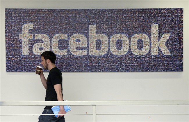 A Facebook employee walks past a sign at Facebook headquarters in Menlo Park, Calif. 
