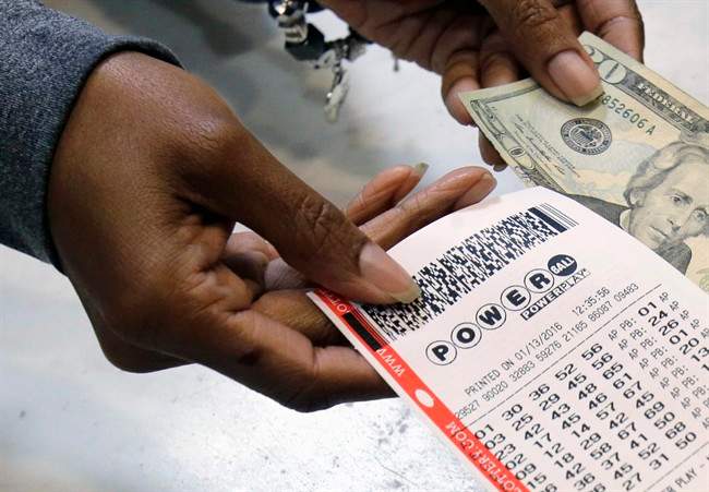 FILE - In this Jan. 13, 2016 file photo, a clerk hands over a Powerball ticket for cash at Tower City Lottery Stop in Cleveland. 