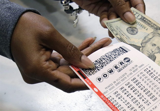FILE - In this Jan. 13, 2016 file photo, a clerk hands over a Powerball ticket for cash at Tower City Lottery Stop in Cleveland. 