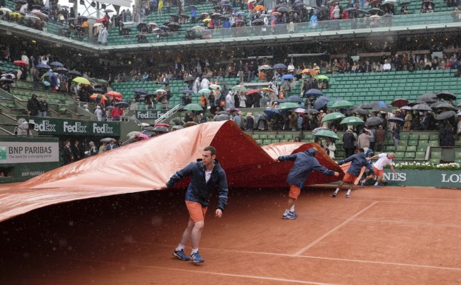 Stadium workers cover the clay court as the fourth round match of the French Open tennis tournament.