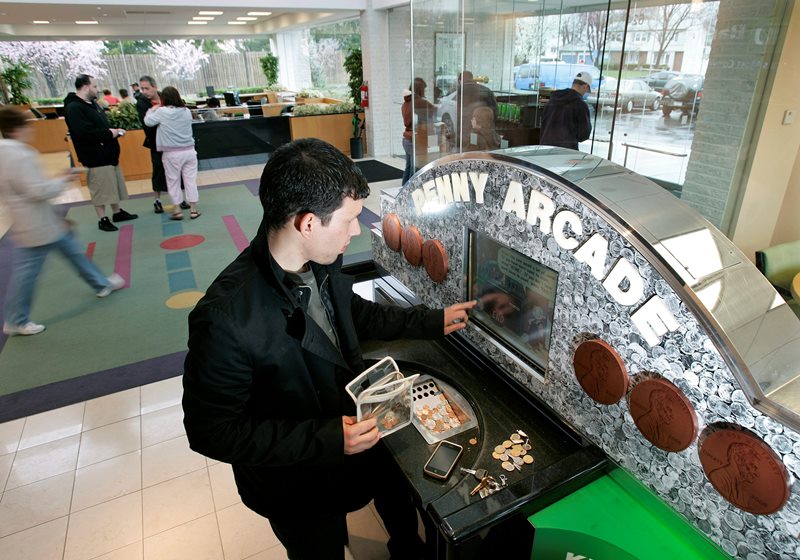 In this April 11, 2009 photo, Charles Acosta puts change in a PennyArcade coin counting machine at a TD Bank branch in Fairless Hills, Pa.