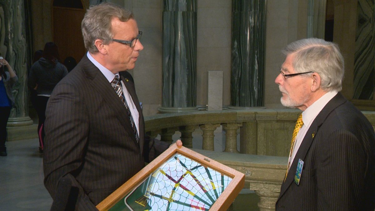 Premier Brad Wall presents Anthony Drake with a flag that flew above the legislature. 