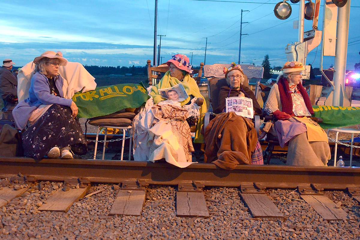 Members of the Seattle Raging Grannies sit in their rocking chairs chained together on the Burlington-Northern Railroad tracks at Farm to Market Road in Skagit County on Friday evening, May 13, 2016, in Burlington, Wash.  