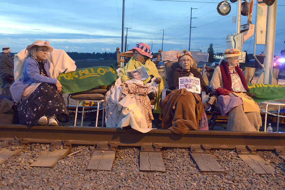 Members of the Seattle Raging Grannies sit in their rocking chairs chained together on the Burlington-Northern Railroad tracks at Farm to Market Road in Skagit County on Friday evening, May 13, 2016, in Burlington, Wash.  