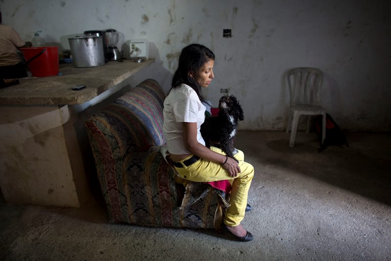  In this May 10, 2016 photo, Argelia Gamboa, Roberto Bernal's widow, sits on a sofa with a family pet, in a hillside slum in Caracas, Venezuela.