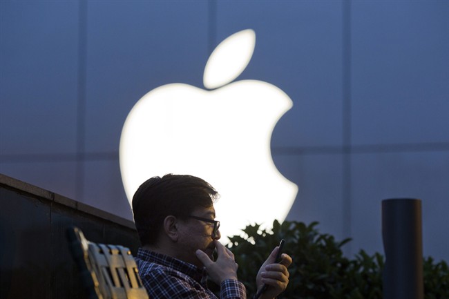 A man uses his mobile phone near a Apple store logo in Beijing, China, Friday, May 13, 2016.