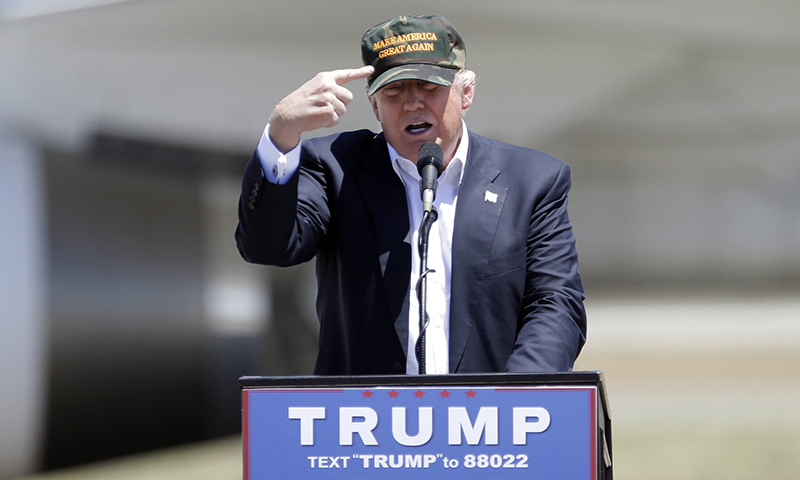 Republican presidential candidate Donald Trump gestures to a his camouflaged "Make America Great" hat as he discuses his support by the National Rifle Association at a campaign rally at the Redding Municipal Airport Friday, June 3, 2016, in Redding, Calif. 