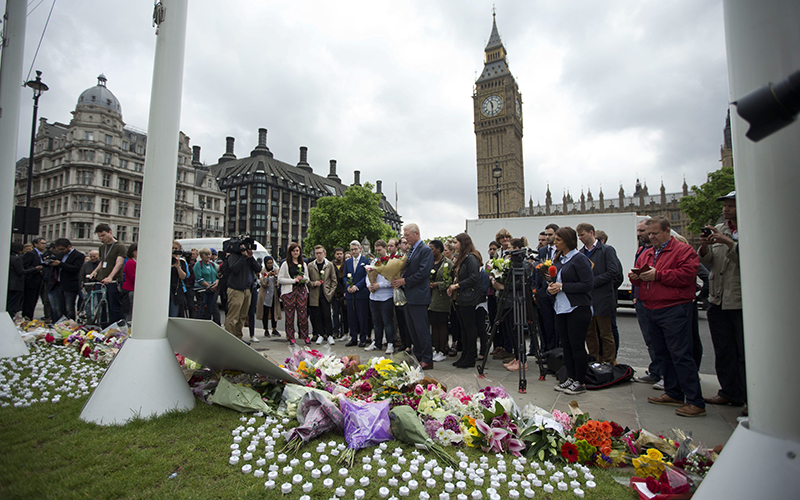Staff from Britain's opposition Labour Party stand together before placing floral tributes for their colleague Jo Cox, the 41-year-old British Member of Parliament shot to death yesterday in northern England, on Parliament Square outside the House of Parliament in London, Friday, June 17, 2016. 