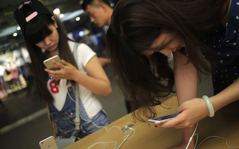 Customers looking at iPhone 6 and iPhone 6 Plus mobile phones in an Apple Store in Beijing, China, 17 June 2016. 