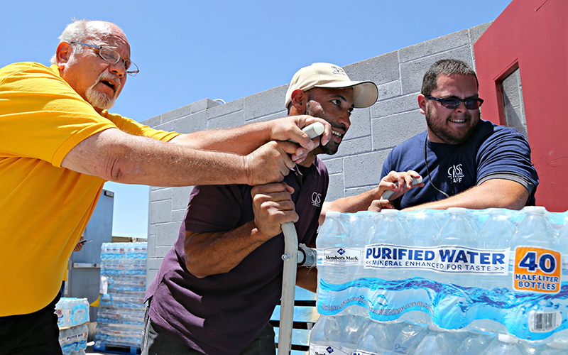 Leo Block, left, Matari Phason, center, and Brian Juarez, right, push part of a shipment of 20,000 water bottles donated by Yellow Cab of Phoenix to Central Arizona Shelter Services, Arizona's largest homeless shelter, to help prepare for the summer heat in Phoenix, Ariz. 