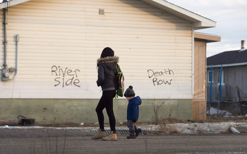 A woman and a child walk through the streets in Attawapiskat, Ont., on Monday, April 16, 2016. Health Canada makes some on-reserve patients jump through hoops or wait longer than non-indigenous Canadians to access prescription drugs their doctors believe they need to treat mental illnesses, a psychiatrist who has worked in First Nations communities says.