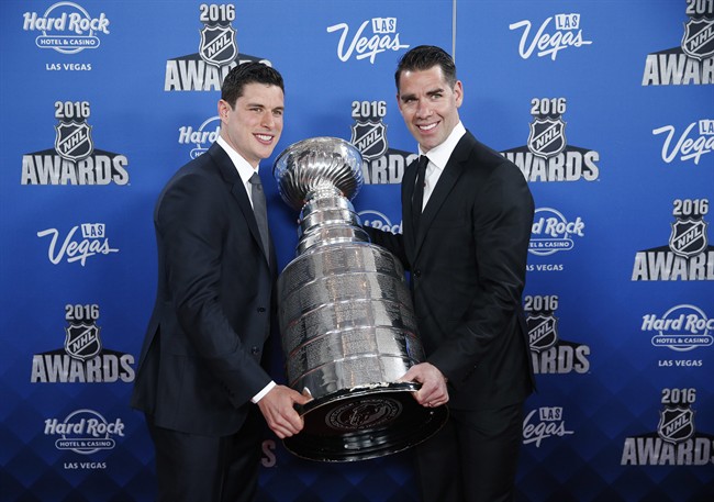 Pittsburgh Penguins' Sidney Crosby, left, and Pascal Dupuis hold up the Stanley Cup on the red carpet before the NHL Awards show, Wednesday, June 22, 2016, in Las Vegas.