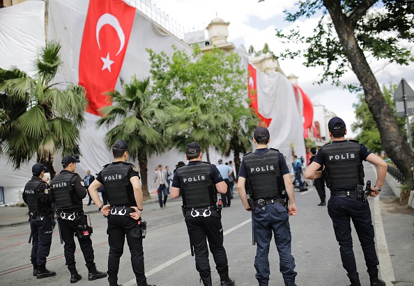 Turkish policemen stand near a hotel building covered with a tarpaulin and Turkish national flags a day after a bomb explosion in Vezneciler district of Istanbul on June 8, 2016.