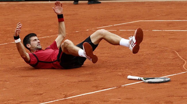 Serbia's Novak Djokovic falls after drawing a hear on the clay and defeating Britain's Andy Murray during their final match of the French Open tennis tournament at the Roland Garros stadium, Sunday, June 5.