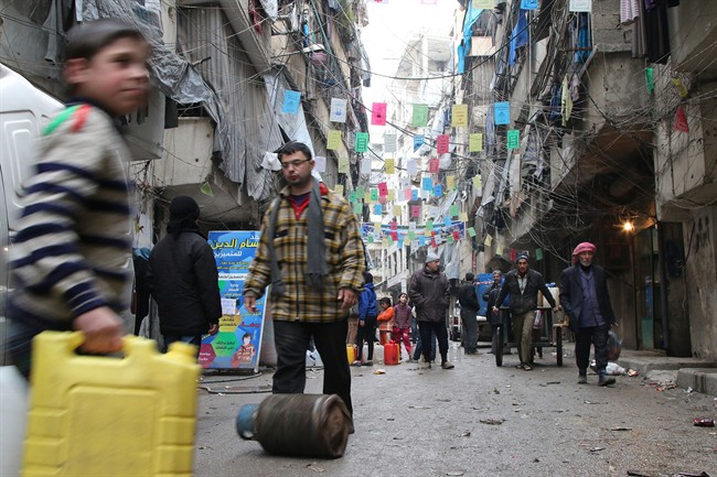 In this Feb. 11, 2016 file photo, civilians carry supplies in Aleppo.