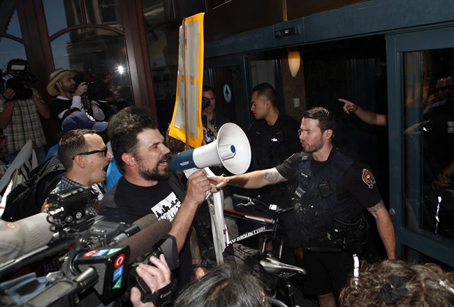Ivan Drury, a spokesperson for Alliance Against Displacement, chants words of support for the homeless in front of Victoria Police at the entrance to the Hotel Grand Pacific near discussions between federal, provincial and territorial ministers about the housing crisis in Canada during a protest in Victoria, B.C., Tuesday, June 28, 2016. 