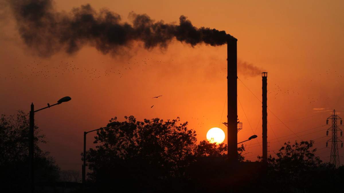 This is a Monday, Dec. 8, 2014 file photo of birds as they fly past at sun set as smoke emits from a chimney at a factory in Ahmadabad, India.