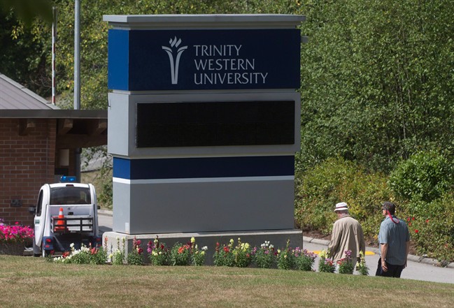 Two men walk past a sign at Trinity Western University in Langley, B.C., on Monday August 24, 2015.