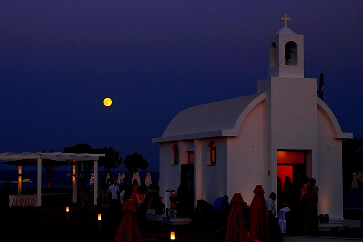 The full moon rises over a small Christian orthodox church during a wedding ceremony at Protaras resort in the southeast part of the island of Cyprus, Saturday, Aug. 29, 2015. 