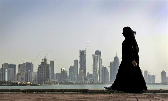 A Qatari woman walks in front of the city skyline in Doha, Qatar.