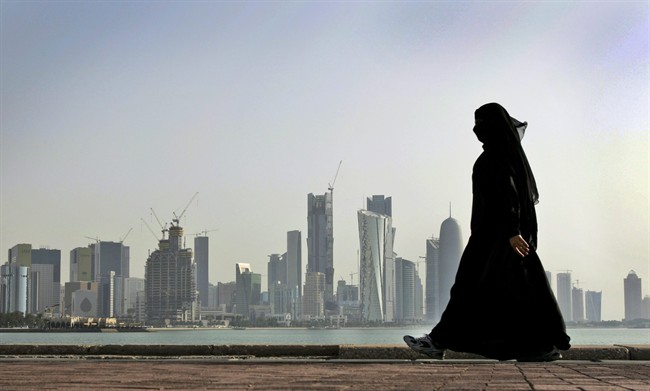A Qatari woman walks in front of the city skyline in Doha, Qatar.