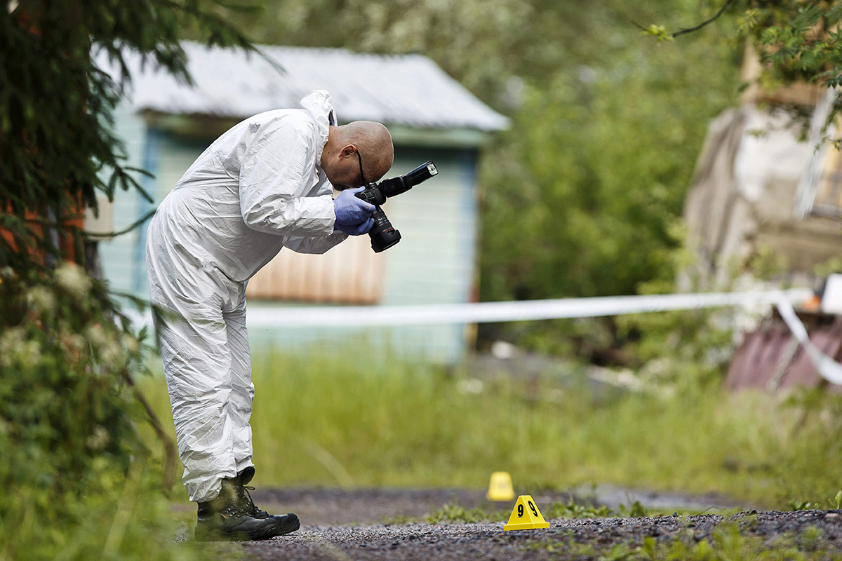 A police investigator takes photographs at the scene of a deadly shooting in Vihti, Finland Saturday, June 18, 2016.