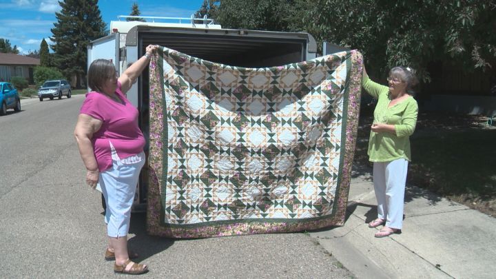 Wilma Mulder and a volunteer hold up one of the 2,500 quilts being sent to Fort McMurray wildfire evacuees. 