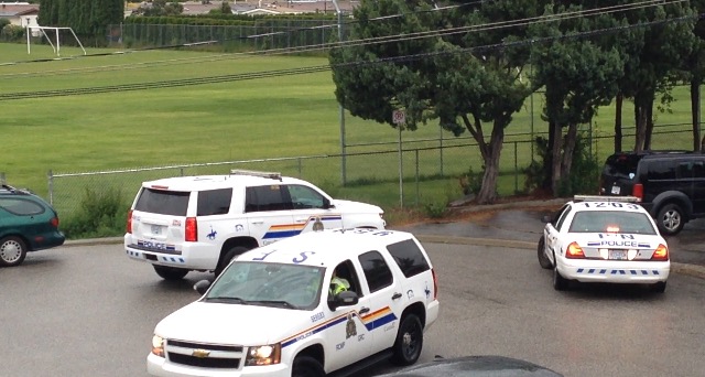 Several police vehicles parked on Waterford Avenue in Penticton on Saturday evening as an RCMP helicopter flew overhead and officers on foot searched the field. 