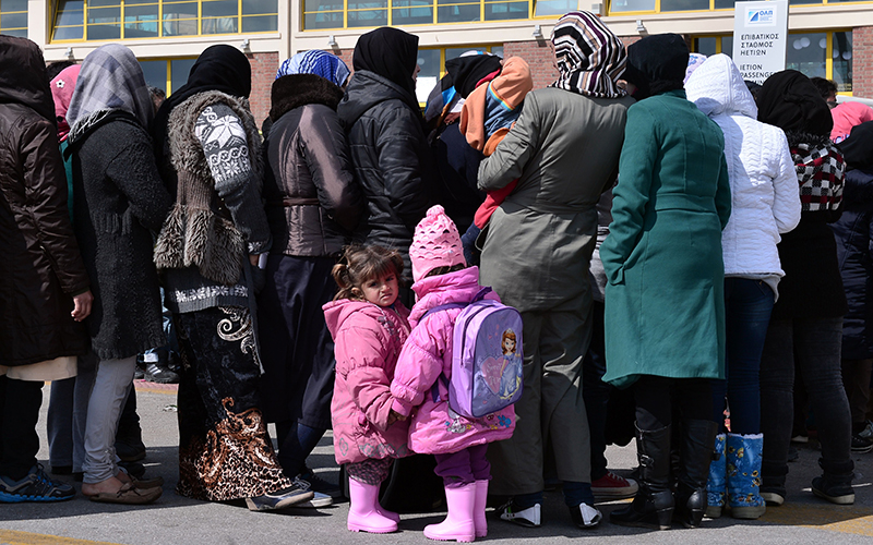 People wait for a red cross aid distribution at the port of Piraeus on March 16, 2016.
