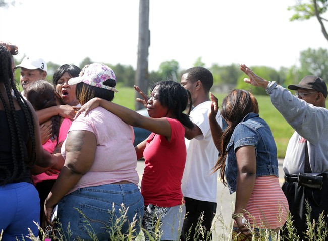 Crystal Mitchell, center the mother of Deontae Mitchell,is surrounded by comforting family and friends pray, Thursday, June 2, at the scene where a body was found in Detroit.