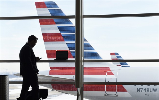 In this Jan. 25, 2016, file photo, a passenger talks on the phone as American Airlines jets sit parked at their gates at Washington's Ronald Reagan National Airport.