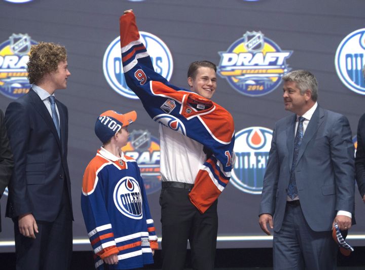 Jesse Puljujarvii, fourth overall pick, pulls on his sweater as he stands on stage with members of the Edmonton Oilers management team at the NHL draft in Buffalo, N.Y. on Friday June 24, 2016. 