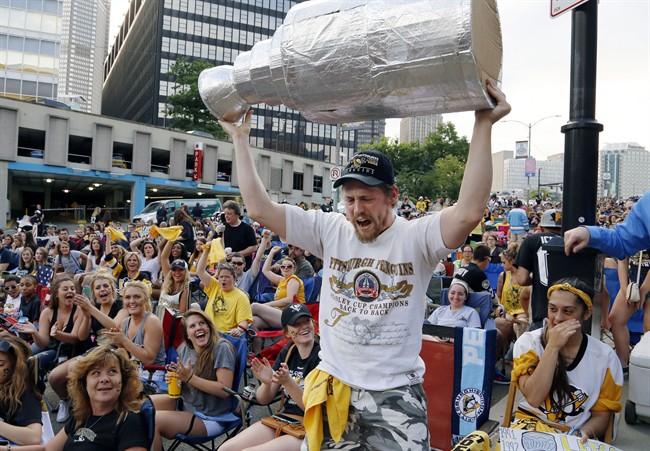 Pittsburgh Penguins fans cheer as Zac Crowe hoists a fake Stanley Cup outside Consol Energy Center before Game 2 of the NHL hockey Stanley Cup Finals between the Penguins and the San Jose Sharks on Wednesday, June 1, 2016, in Pittsburgh.