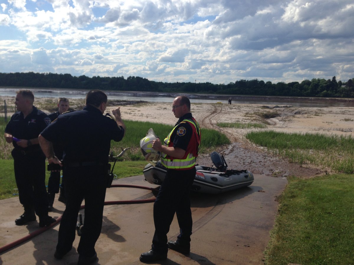 Officials gather on the banks of the Petitcodiac River after a body was recovered Wednesday afternoon.