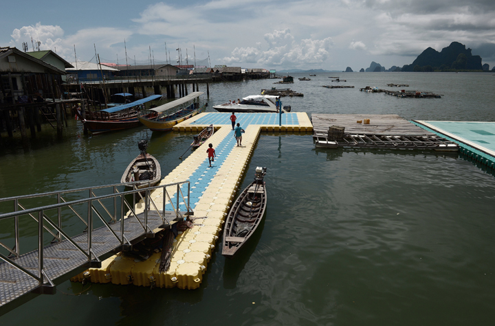 This picture taken on October 2, 2014 shows children running on a ponton to sell souvenirs to tourists disembarking from a speedboat as they arrive on Koh Panyee, in Thailand' southern Phang Nga province.