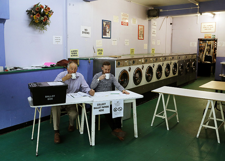 A presiding officer and poll clerk drink a cup of tea while waiting for early morning voters at a polling station set up in a launderette in Headington outside Oxford on June 23, 2016 as the U.K. votes on leaving the European Union.