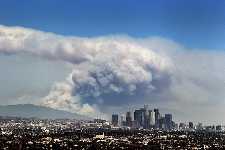Smoke from wildfires burning in Angeles National Forest fills the sky behind the Los Angeles skyline on Monday, June 20, 2016.